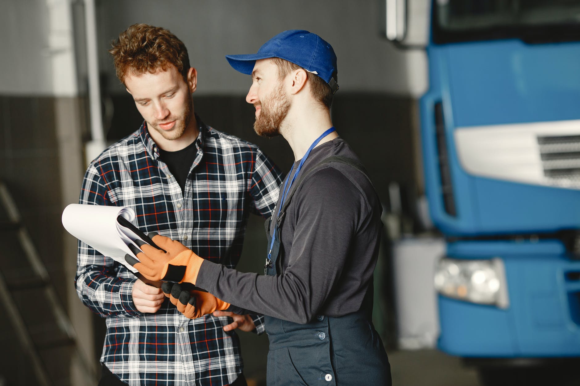 Mechanic holding a clip board, explaining to a customer what repairs are being made